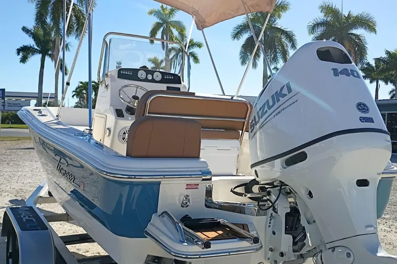 Slide: The Image of 2026 Pioneer 180 Sportfish boat with Suzuki 140 outboard motor, parked under palm trees. - 3