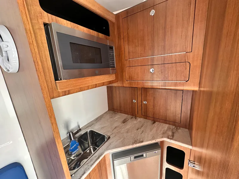 Slide: The Image of Compact kitchen area in 2017 Invincible 42 Center Cabin boat with microwave, sink, and storage. - 31