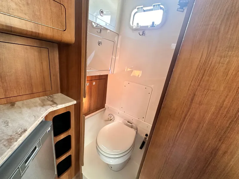 Slide: The Image of 2017 Invincible 42 Center Cabin boat bathroom with wooden cabinetry and a small window. - 32
