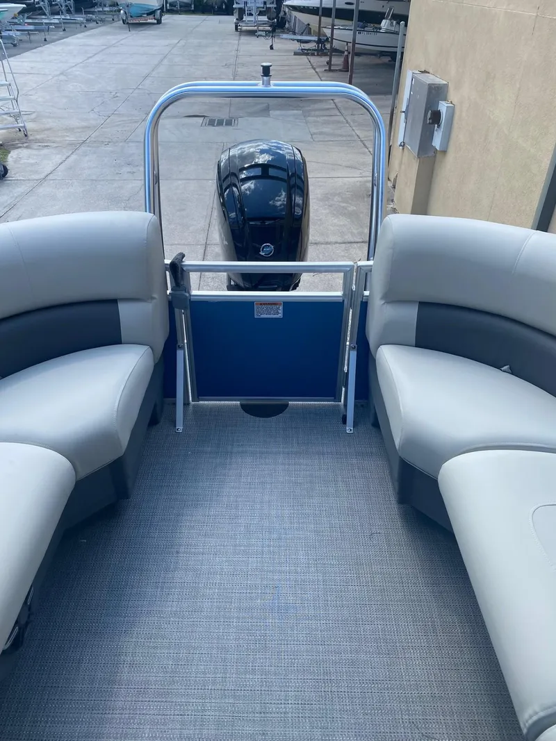 Slide: The Image of 2024 Starcraft LX 20 R pontoon boat interior with seating and outboard motor. - 5