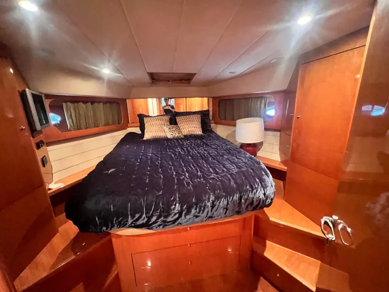 Slide: The Image of Luxurious bedroom in a 2001 Uniesse Flybridge 48 yacht with wood paneling and ambient lighting. - 24