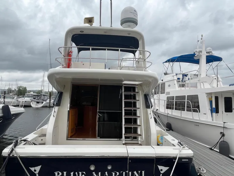Slide: The Image of Uniesse Flybridge 48 (2001) yacht docked at marina, rear view with ladder and upper deck. - 4