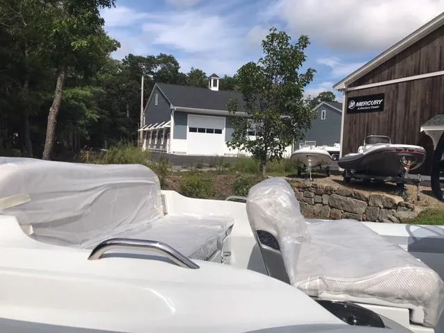 Slide: The Image of 2024 Zar Formenti 53 boat with covered seats, parked near a Mercury dealership. - 5