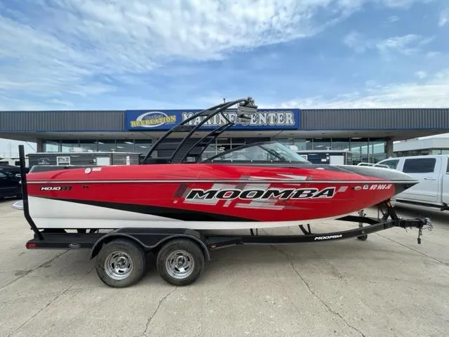 Slide: The Image of 2012 Moomba Mojo 2.5 red and white boat on a trailer outside a marine center. - 5