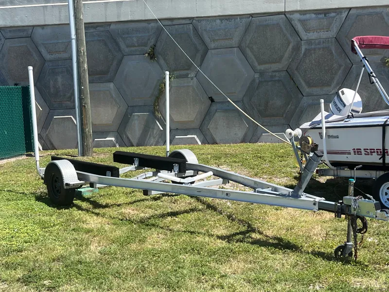 Slide: The Image of Boat trailer for 2009 Boston Whaler 190 Outrage on grass near concrete wall. - 10