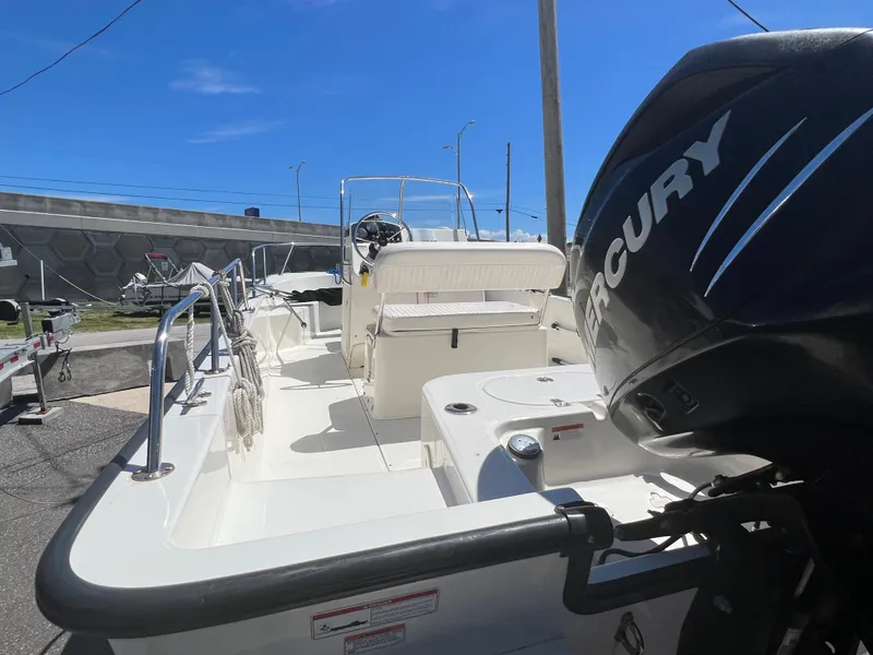 Slide: The Image of 2009 Boston Whaler 190 Outrage boat with Mercury outboard motor, docked under clear blue sky. - 7