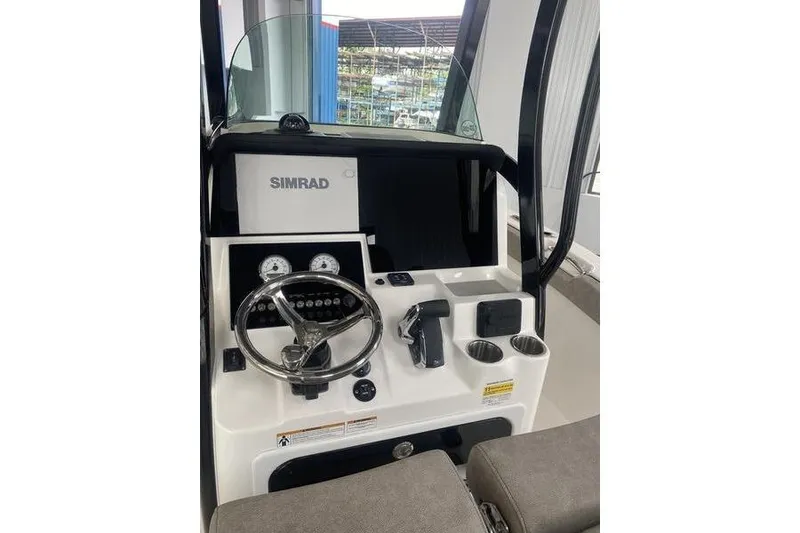 Slide: The Image of 2024 Sea Pro 242 Center Console boat dashboard with Simrad display and steering wheel. - 22