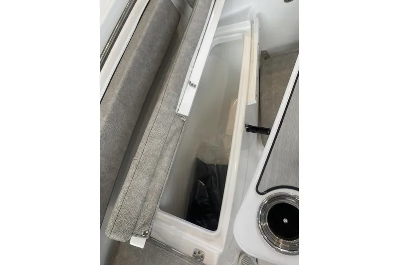Slide: The Image of 2024 Sea Pro 242 Center Console boat storage compartment with open lid and cup holder. - 44