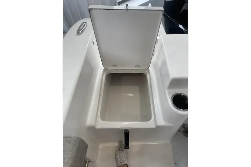 Slide: The Image of 2024 Sea Pro 242 Center Console storage compartment with open lid and cup holder. - 56