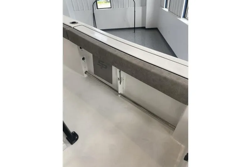 Slide: The Image of 2024 Sea Pro 242 Center Console boat interior with cushioned seating and storage compartment. - 58