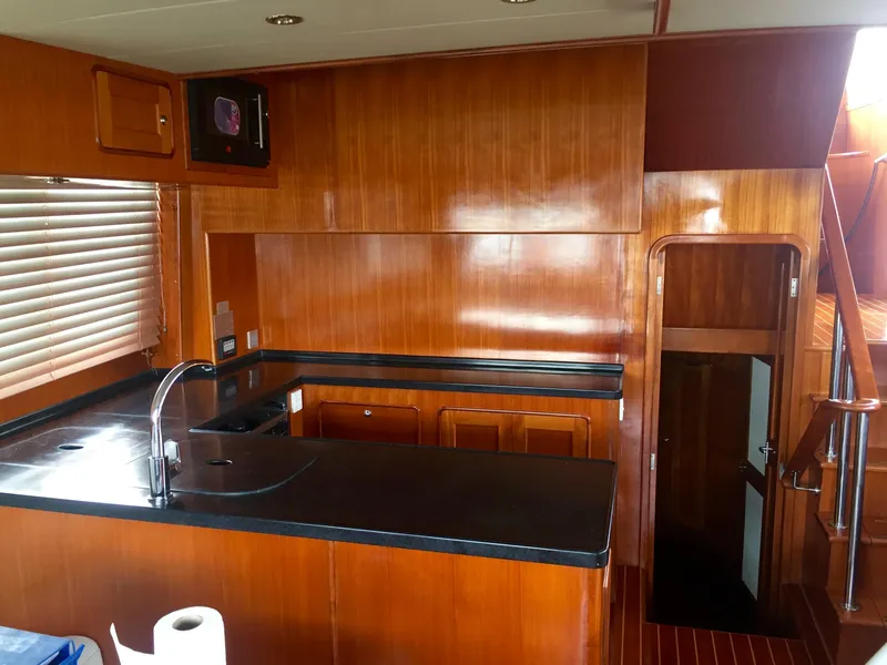Slide: The Image of 2012 Integrity 45 yacht kitchen with wooden cabinetry and black countertops. - 18