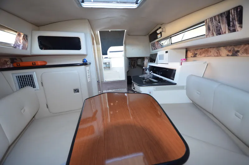 Slide: The Image of 2000 Chaparral Signature 270 cabin interior with seating, table, and kitchenette. - 12