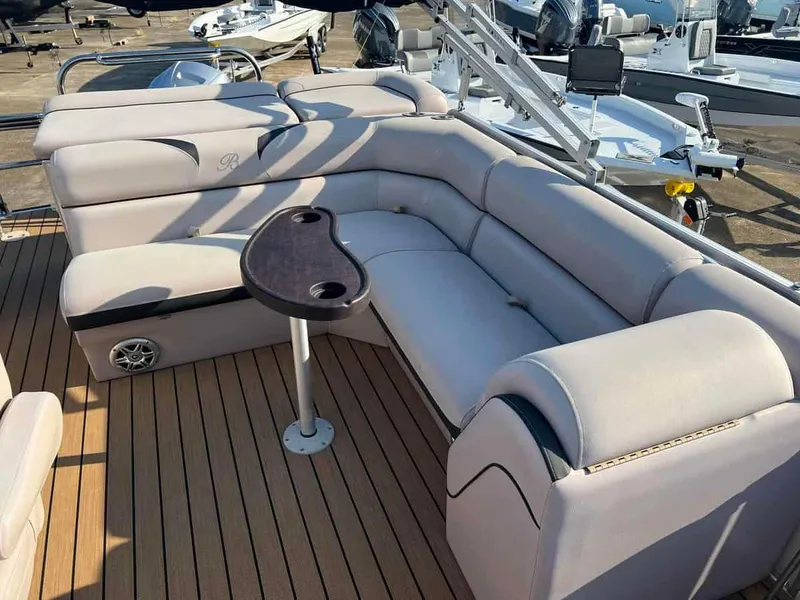 Slide: The Image of 2015 Berkshire 230 CL boat interior with beige seating and a small table. - 7