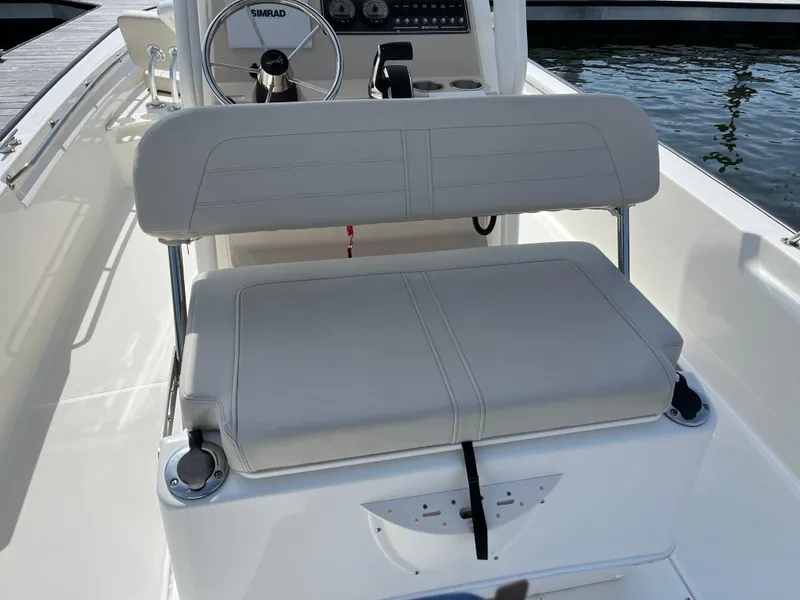 Slide: The Image of 2024 Boston Whaler 210 Montauk boat interior with cushioned seating and steering console. - 14