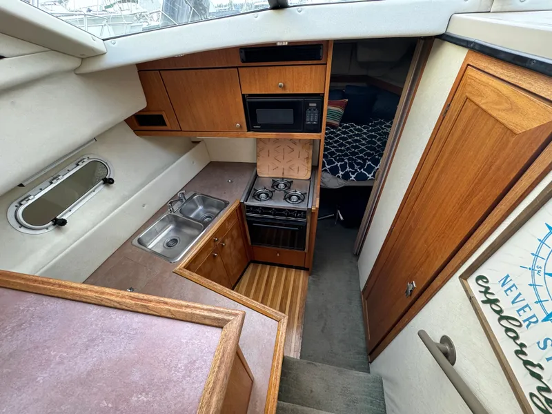 Slide: The Image of 1996 Bayliner 3388 Command Bridge Motoryacht kitchen area with stove, sink, and microwave. - 11