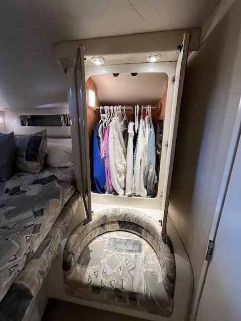 Slide: The Image of 1997 Sea Ray 500 Sundancer cabin closet with hanging clothes and cushioned seat. - 10