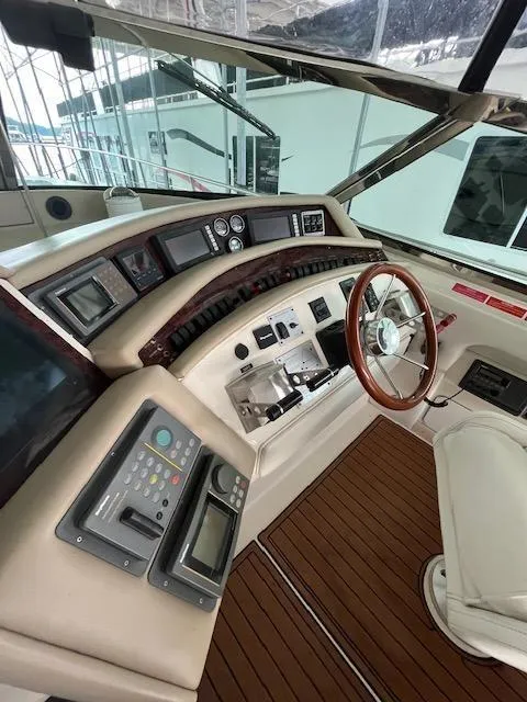 Slide: The Image of 1997 Sea Ray 500 Sundancer helm with advanced navigation controls and wooden steering wheel. - 4