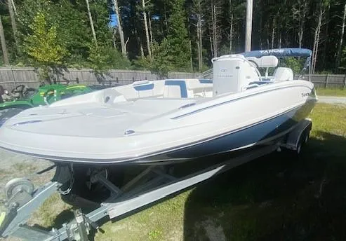 Slide: The Image of 2024 Tahoe 2150 CC boat on trailer, parked outdoors, surrounded by trees. - 2