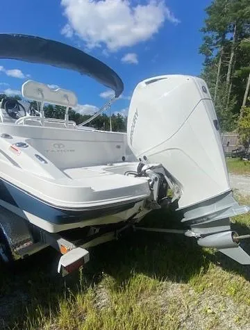 Slide: The Image of 2024 Tahoe 2150 CC boat with outboard motor, parked outdoors under blue sky. - 4