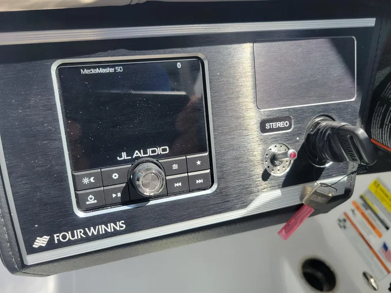 Slide: The Image of 2024 Four Winns HD5 OB boat dashboard with JL Audio system and stereo controls. - 11