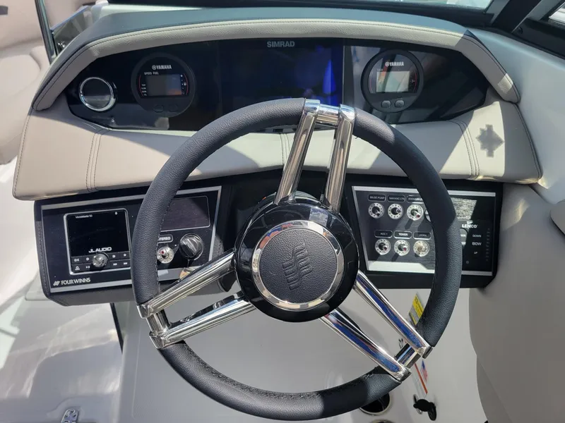 Slide: The Image of 2024 Four Winns HD5 OB boat dashboard with steering wheel and control panels. - 9