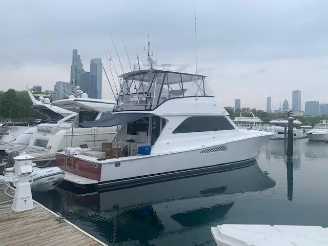 Slide: The Image of 2002 Viking 55 Convertible yacht docked in a marina with city skyline background. - 12