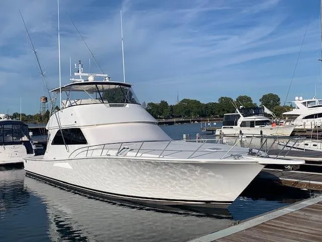 Slide: The Image of 2002 Viking 55 Convertible yacht docked at marina under clear blue sky. - 5