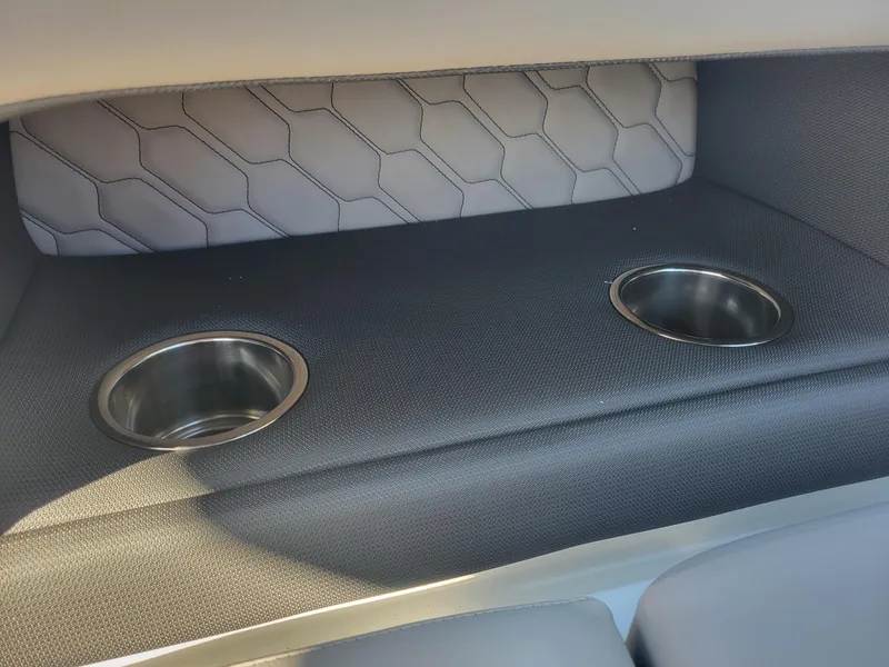 Slide: The Image of 2024 Four Winns H1 OB boat interior with dual cup holders and hexagonal pattern upholstery. - 37