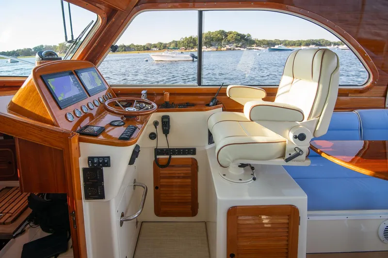 Slide: The Image of 2005 Hinckley Talaria 40 yacht deck with blue seating and American flag, overlooking a marina. - 17