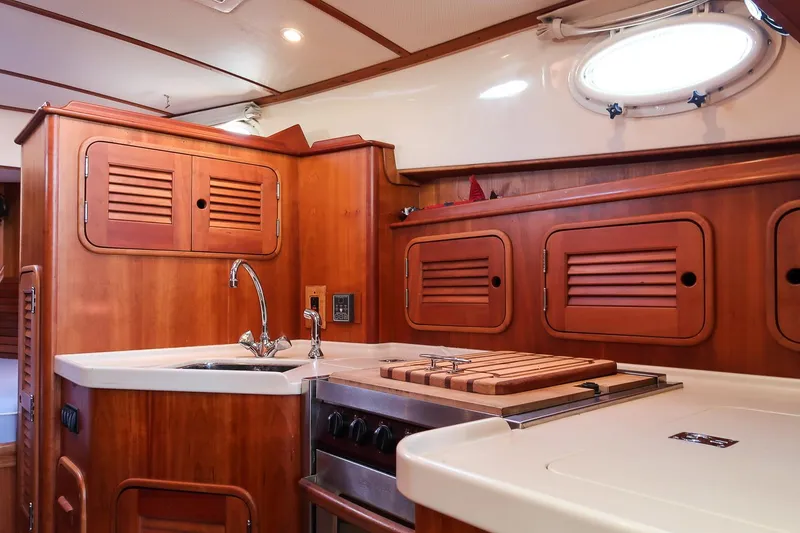 Slide: The Image of 2005 Hinckley Talaria 40 yacht interior with wooden cabinetry and compact kitchen area. - 25
