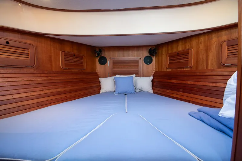 Slide: The Image of 2005 Hinckley Talaria 40 cabin interior with wooden finish and cozy bedding. - 29