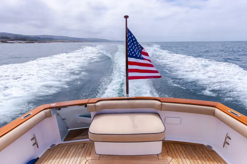 Slide: The Image of 2014 San Juan Open Express Cruiser with American flag on open sea. - 13