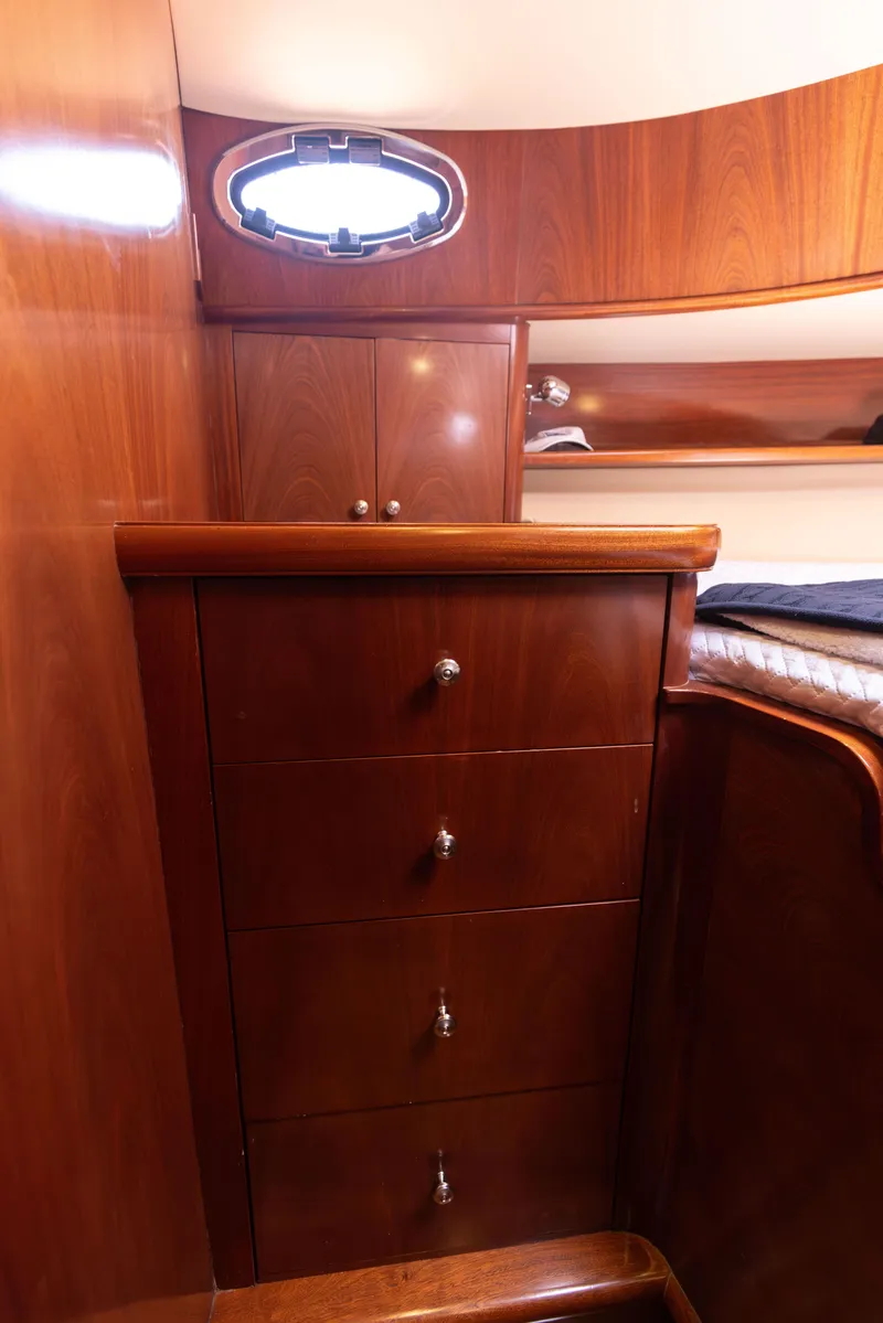 Slide: The Image of 2014 San Juan Open Express Cruiser cabin with wooden drawers and porthole window. - 27