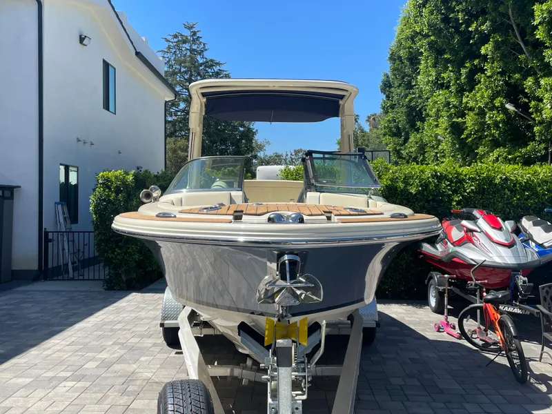 Slide: The Image of 2022 Chris-Craft Launch 25 GT boat on trailer in driveway, surrounded by greenery. - 3