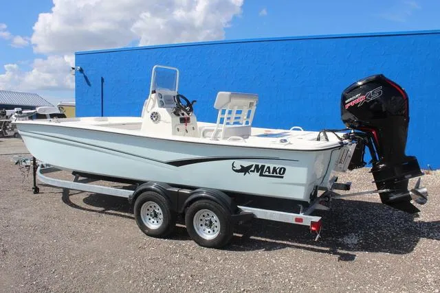 Slide: The Image of 2024 Mako Pro Skiff 19 CC on trailer, side view against blue wall. - 7