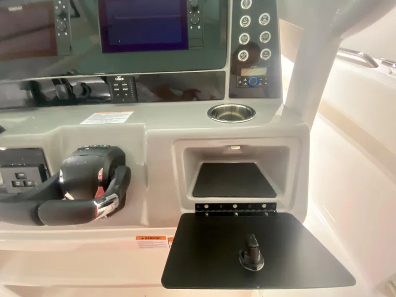 Slide: The Image of 2024 Robalo R270 boat dashboard with controls and storage compartment. - 20