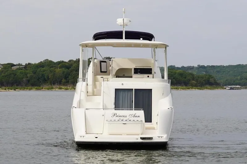 Slide: The Image of 2008 Meridian 459 Motoryacht on water, rear view, with lush green shoreline in background. - 6