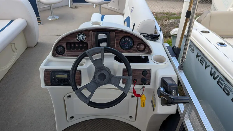 Slide: The Image of Steering console of a 2016 Avalon 2480 QF boat with wood accents and controls. - 12