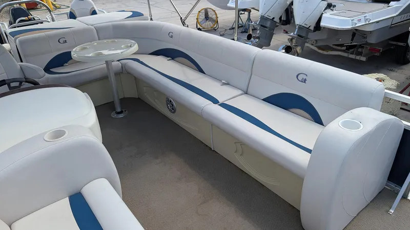Slide: The Image of 2016 Avalon 2480 QF boat interior with white and blue seating and a small table. - 15