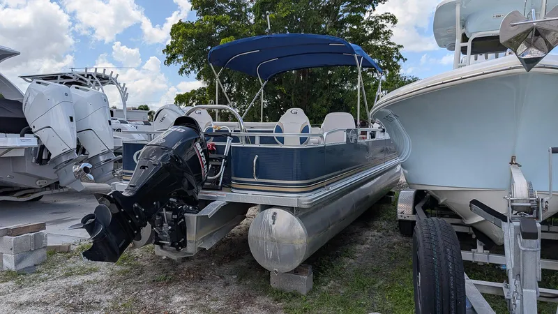 Slide: The Image of 2016 Avalon 2480 QF pontoon boat with outboard motor, parked beside other boats. - 6