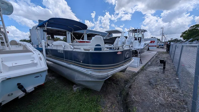 Slide: The Image of 2016 Avalon 2480 QF pontoon boat parked outdoors under a cloudy sky. - 7
