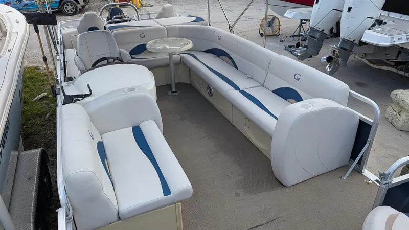 Slide: The Image of 2016 Avalon 2480 QF pontoon boat interior with white and blue seating and table. - 8