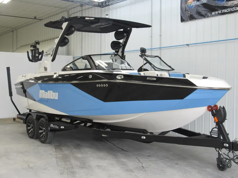 Slide: The Image of 2024 Malibu 23 LSV boat in showroom, black and blue design, on trailer. - 3