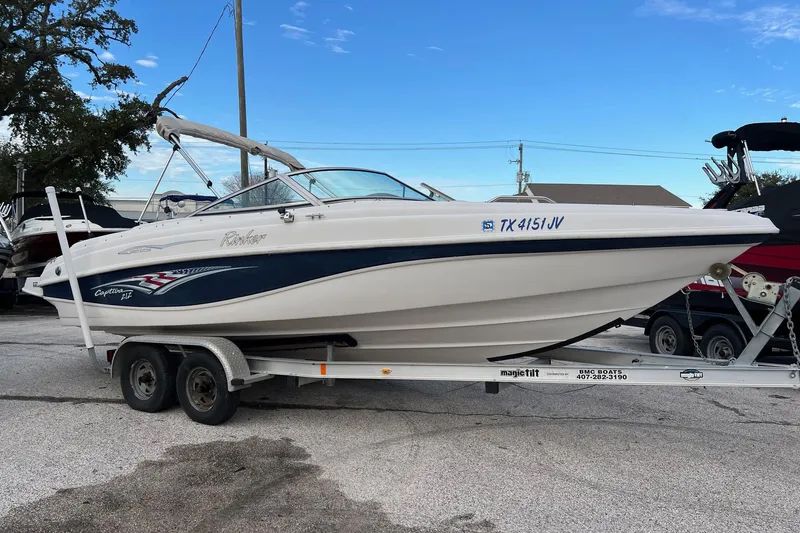 The Image of 2002 Rinker 212 BR boat on trailer, parked outdoors. - 0