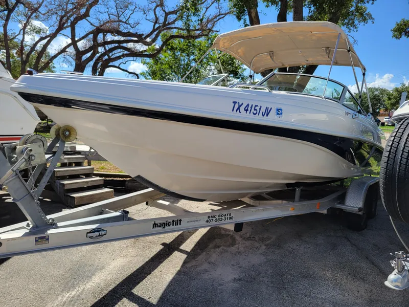 Slide: The Image of 2002 Rinker 212 BR boat on a trailer with a canopy, parked outdoors. - 1