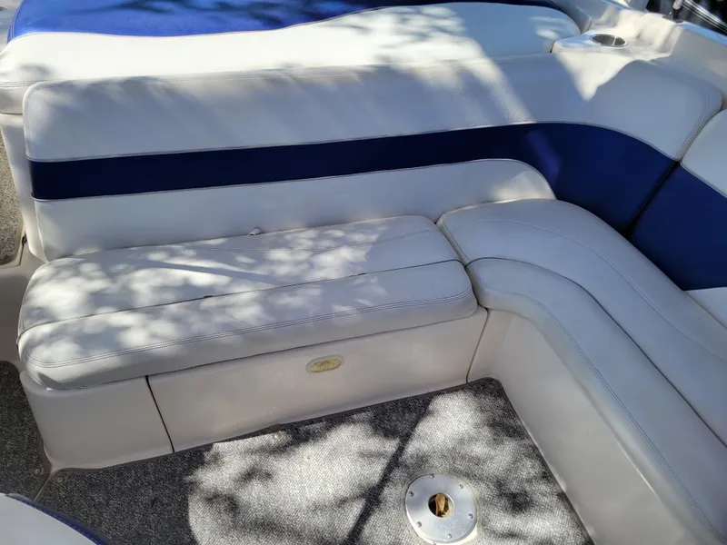 Slide: The Image of 2002 Rinker 212 BR boat interior with white and blue cushioned seating. - 7