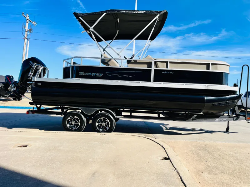 Slide: The Image of 2024 Ranger Reata 200C pontoon boat with black exterior and canopy on trailer. - 5