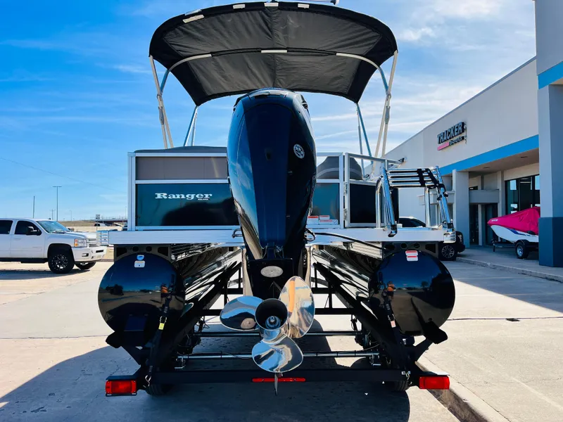 Slide: The Image of 2024 Ranger Reata 200C pontoon boat with outboard motor, docked at a dealership. - 7