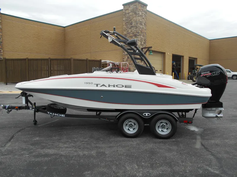Slide: The Image of 2024 Tahoe 1950 boat on trailer, side view, parked near a building. - 2