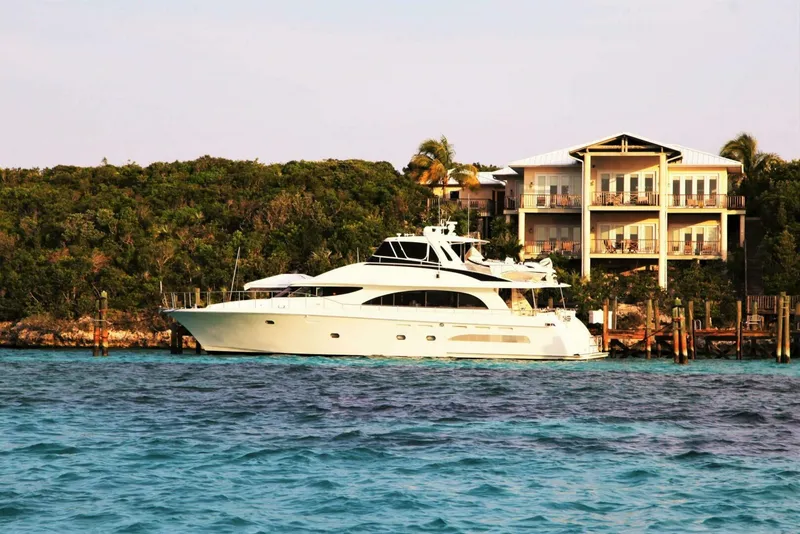 Slide: The Image of 1998 Cheoy Lee 81 Motor Yacht docked near a luxurious waterfront property. - 2